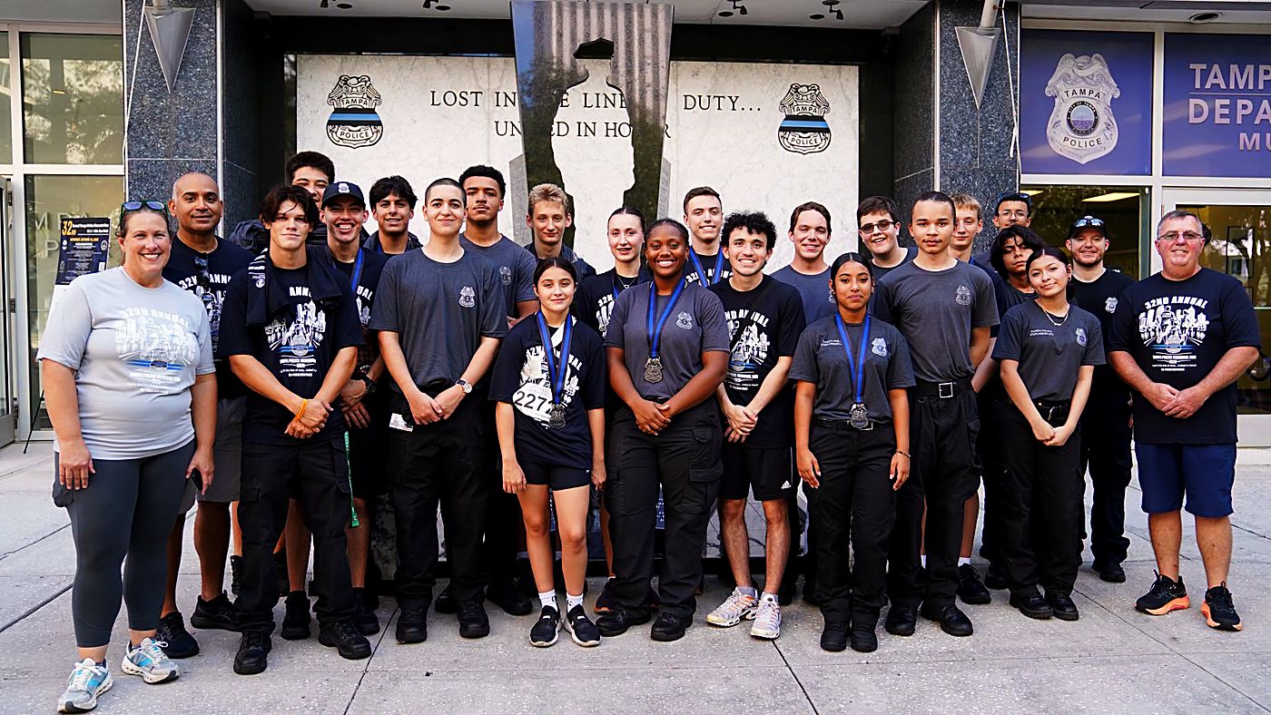 Tampa Police Explorers with finisher medals in front of the memorial monument at police headquarters